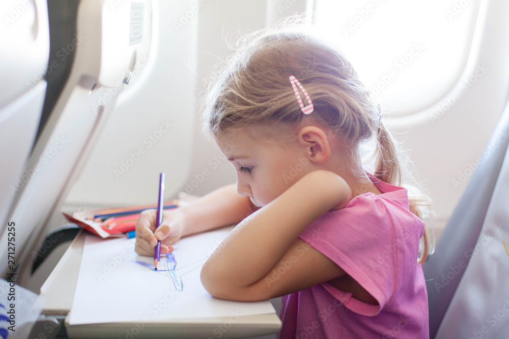 Kid draws in an airplane. Children leisure in flight. Girl is traveling. Kid draws in an airplane. Children leisure in flight. Girl is traveling.