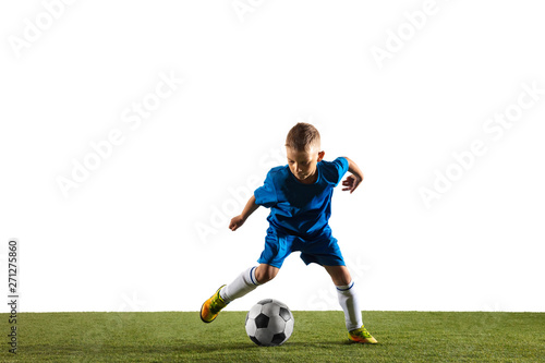 Young boy as a soccer or football player in sportwear making a feint or a kick with the ball for a goal on white studio background. Fit playing boy in action, movement, motion at game.