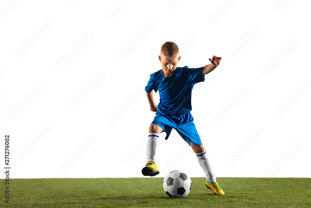 Obraz premium Young boy as a soccer or football player in sportwear making a feint or a kick with the ball for a goal on white studio background. Fit playing boy in action, movement, motion at game.
