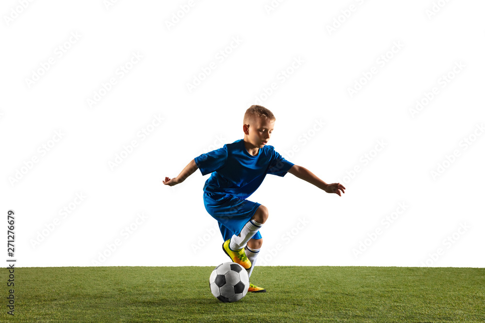 Young boy as a soccer or football player in sportwear making a feint or a kick with the ball for a goal on white studio background. Fit playing boy in action, movement, motion at game.