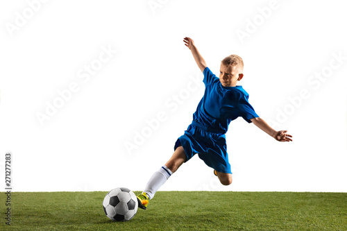 Young boy as a soccer or football player in sportwear making a feint or a kick with the ball for a goal on white studio background. Fit playing boy in action, movement, motion at game. © master1305