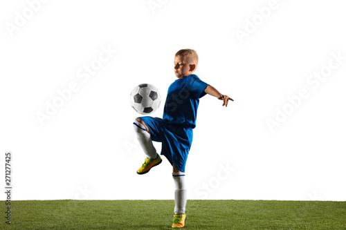 Young boy as a soccer or football player in sportwear making a feint or a kick with the ball for a goal on white studio background. Fit playing boy in action, movement, motion at game. photo