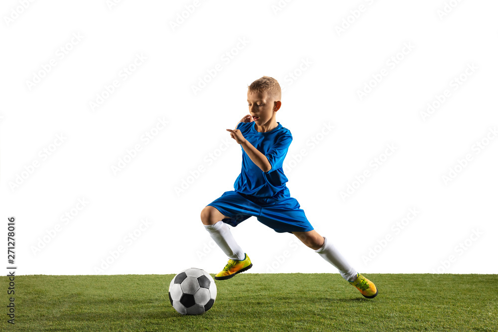 Young boy as a soccer or football player in sportwear making a feint or a kick with the ball for a goal on white studio background. Fit playing boy in action, movement, motion at game.