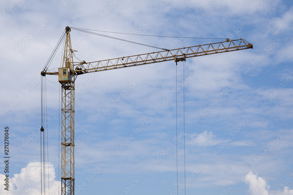 Industrial construction building crane against blue cloudy sky