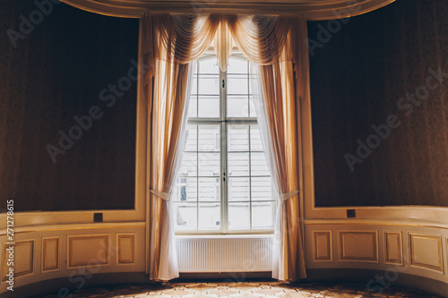 wooden windows with vintage curtains and square moldings on a sunny day. beige satin curtains. interior of an empty room with expensive decoration. background for collage