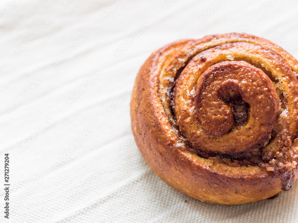 Fototapeta premium Confectionery baking. Sweet fresh soft roll bun with cinnamon on white background. Cinnabon closeup