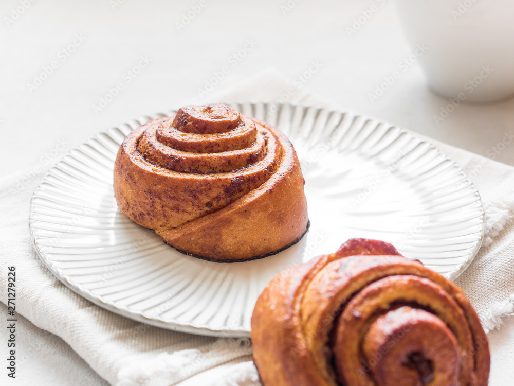 Confectionery baking. Sweet fresh soft roll bun with cinnamon on white background. Cinnabon closeup Confectionery baking. Sweet fresh soft roll bun with cinnamon on white background. Cinnabon closeup