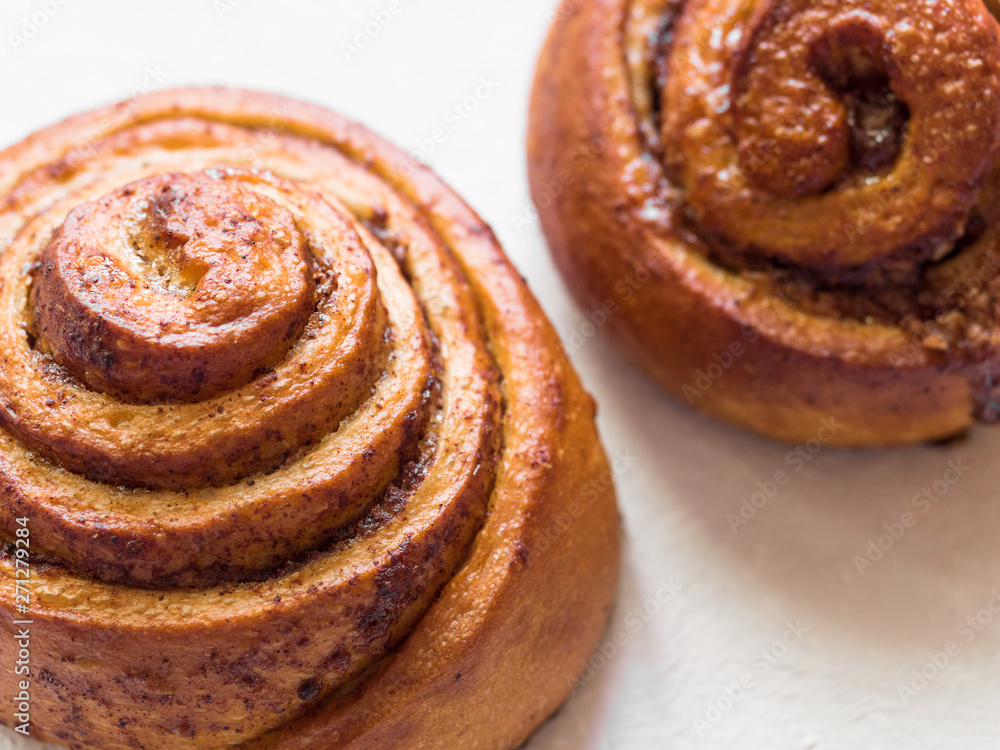 Fototapeta premium Confectionery baking. Sweet fresh soft roll bun with cinnamon on white background. Cinnabon closeup