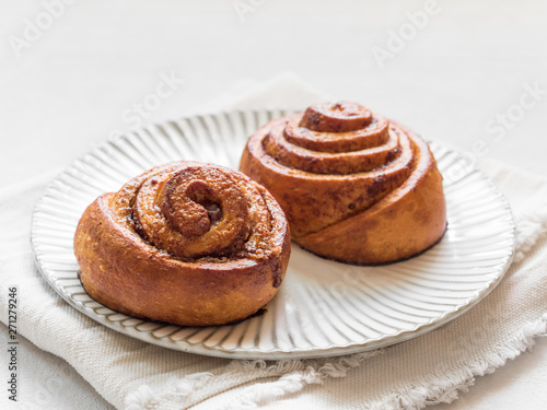 Confectionery baking. Sweet fresh soft roll bun with cinnamon on white background. Cinnabon closeup