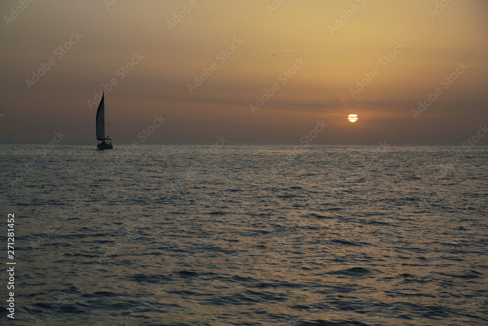 Fototapeta premium The yacht stands in the sea against a picturesque sunset