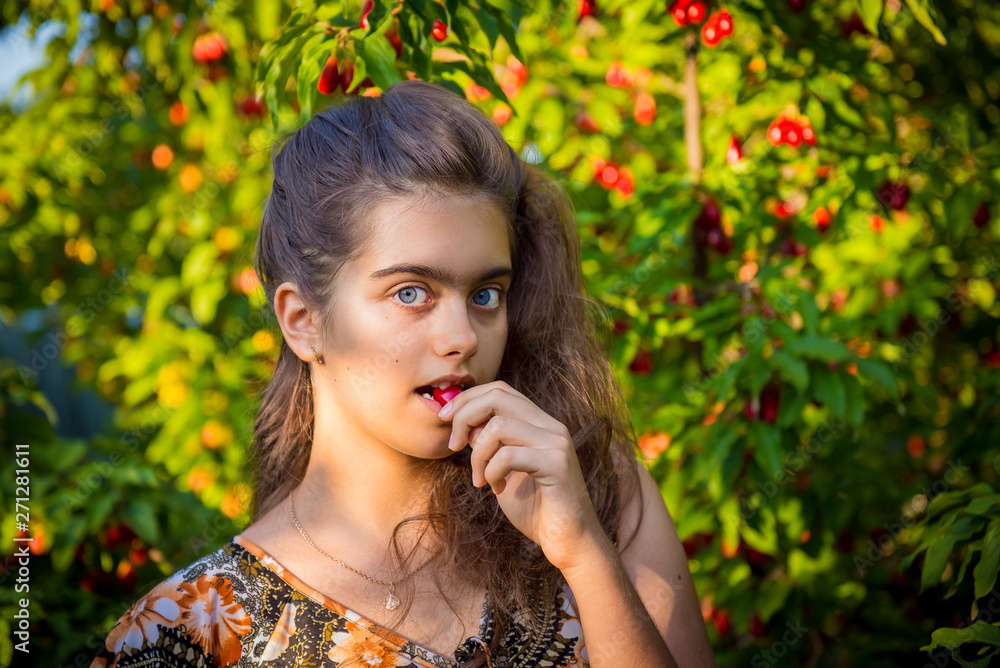Sweet Girl Eats Cherry in the Garden. Young girl and sweet cherry. Portret beautiful girl in the cherry orchard. Sweet cherry. Fruit picking season. Summer fruits. Natural Vitamins Sweet Girl Eats Cherry in the Garden. Young girl and sweet cherry. Portret beautiful girl in the cherry orchard. Sweet cherry. Fruit picking season. Summer fruits. Natural Vitamins