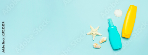 Summer concept, marine background. Seashells, starfish, sunscreen body cream spray on pastel blue background. Top view, flat lay, copy space. Sea summer vacation Mockup. Travel, marine souvenir