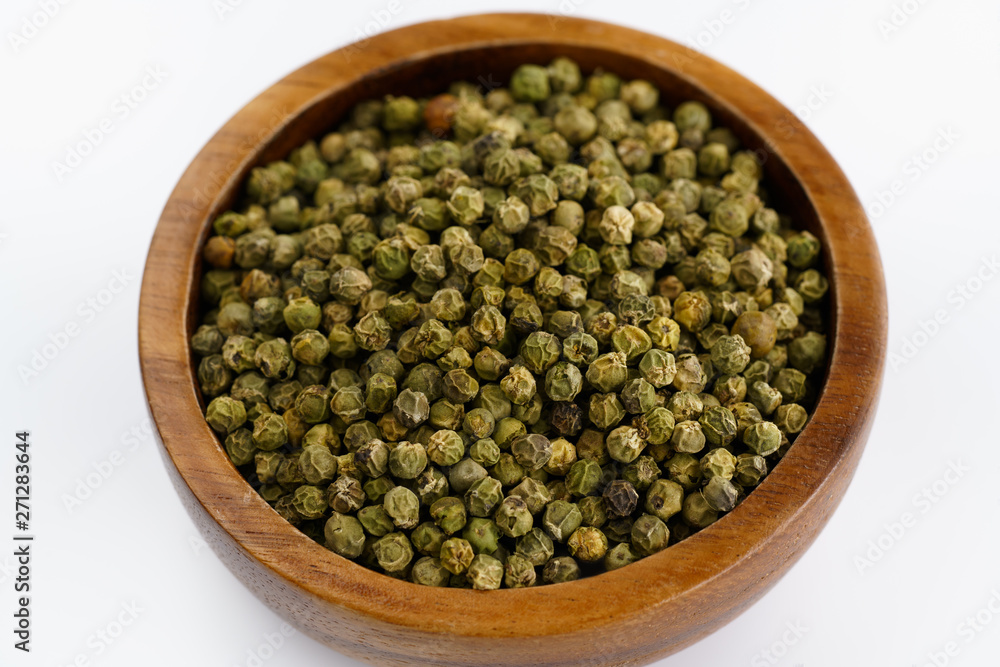 Dried green peppercorns in a wooden bowl. White background, high resolution Dried green peppercorns in a wooden bowl. White background, high resolution