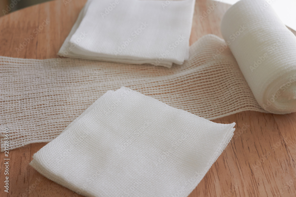 Gauzes and roll gauze on wooden table Gauzes and roll gauze on wooden table