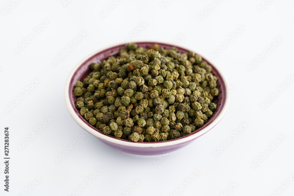 Dried green peppercorns in a violet bowl. White background, high resolution Dried green peppercorns in a violet bowl. White background, high resolution