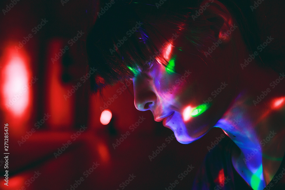 Beautiful girl in the dark with colorful disco light on her face