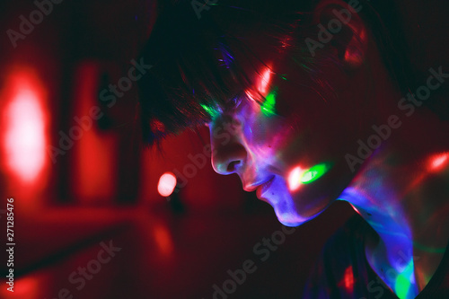 Beautiful girl in the dark with colorful disco light on her face © Amina