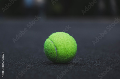 green tennis ball lying on the road