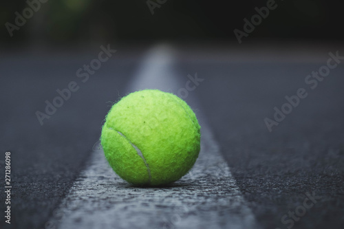 green tennis ball lying on the road along the center on a white strip