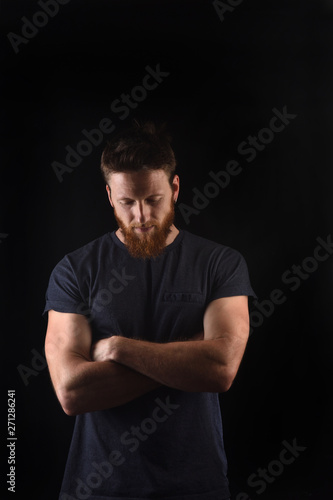portrait of a man look down and with arms crossed and black background