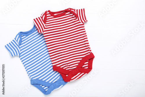 Baby bodysuits on white wooden table