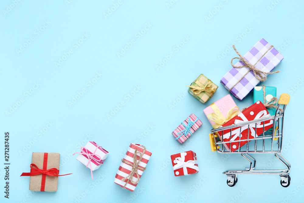 Small shopping cart with gift boxes on blue background Small shopping cart with gift boxes on blue background