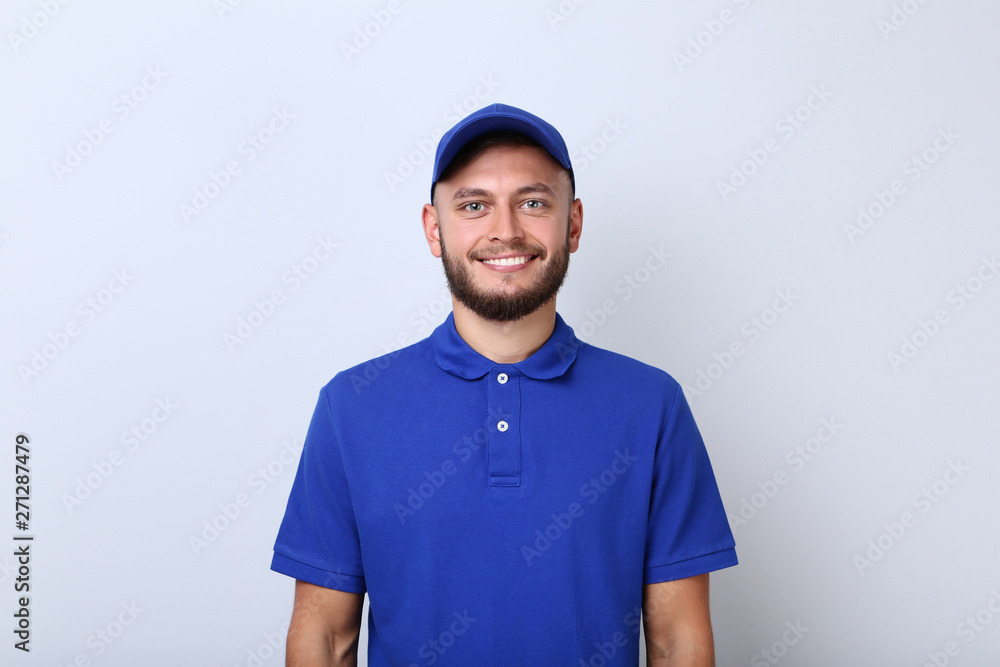 Delivery man in blue uniform on grey background Delivery man in blue uniform on grey background