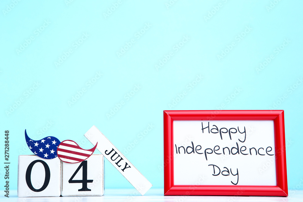 Obraz premium Text Happy Independence Day with cube calendar and paper mustache on blue background