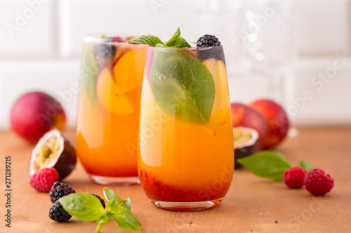 Summer cold peach cocktail or mocktail with basil, raspberry and blackberry photo