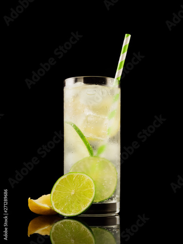 Citrus summer cold coctail or lemonad with ice on black background. Studio shot. Alcohol tasty drink.