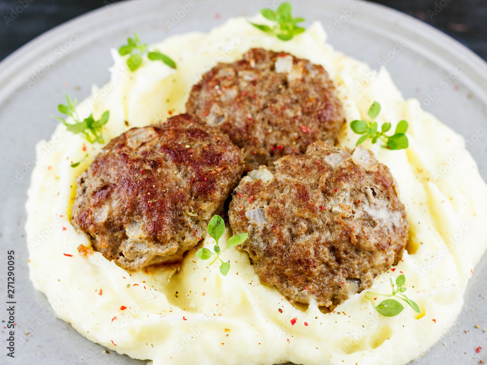 Mashed potatoes and meat balls on a gray plate, decorated with fresh basil Mashed potatoes and meat balls on a gray plate, decorated with fresh basil