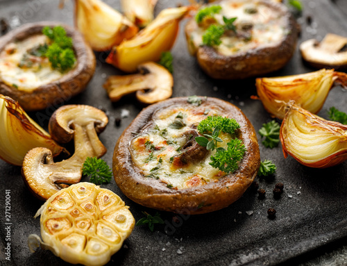Foto Baked portobello mushrooms stuffed with cheese and herbs on a black background, close-up