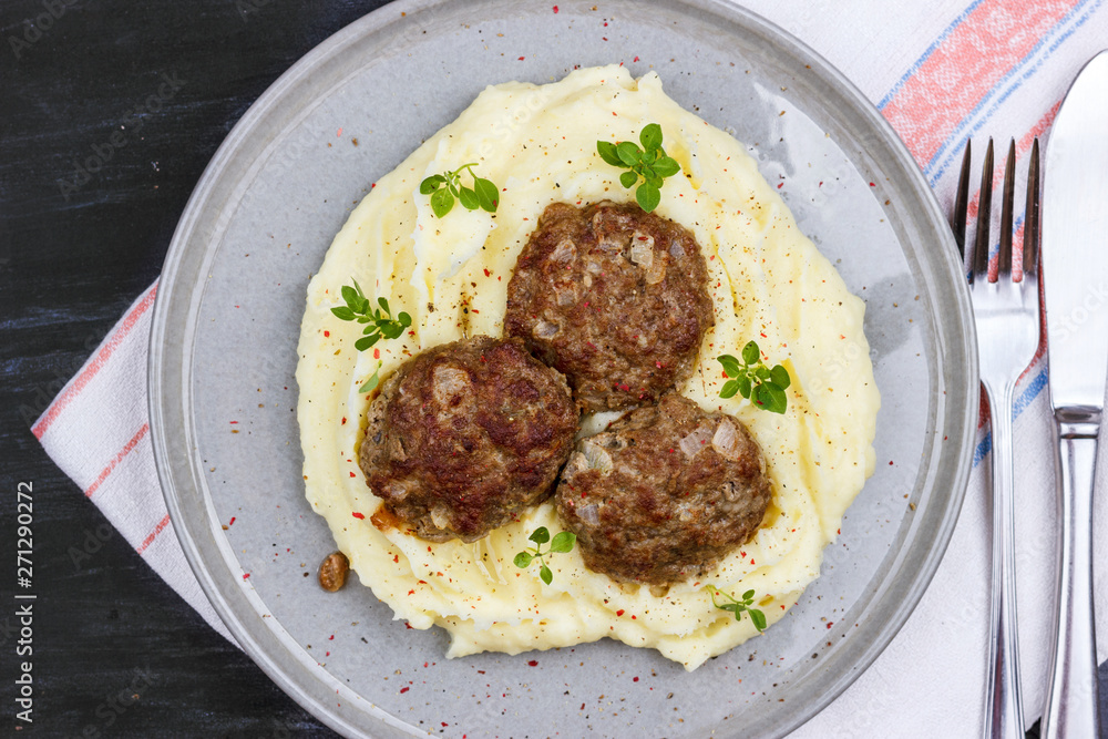 Mashed potatoes and meat balls on a gray plate, decorated with fresh basil Mashed potatoes and meat balls on a gray plate, decorated with fresh basil