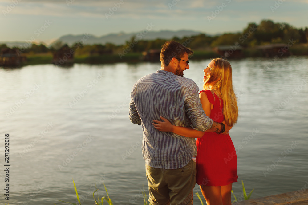 Young couple in love flirting by the river at sunset Young couple in love flirting by the river at sunset