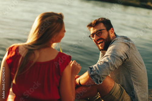 Young couple in love flirting by the river at sunset photo