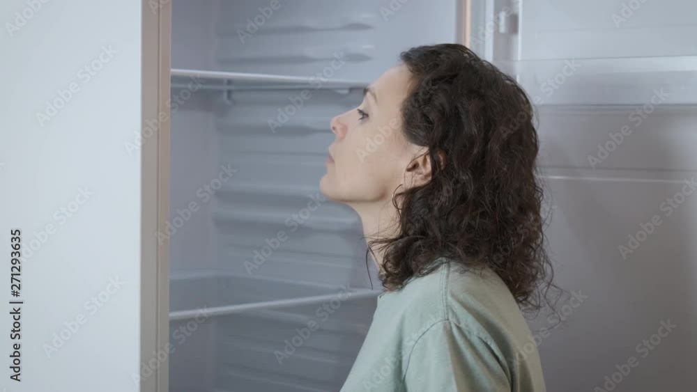 Insufficient of money. A woman looks into an empty refrigerator and gets upset. Poverty. Insufficient of money. A woman looks into an empty refrigerator and gets upset. Poverty.