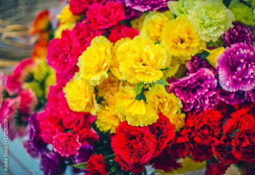 Beautiful colorful – yellow, red and purple artificial flowers – carnations. Abstract background.