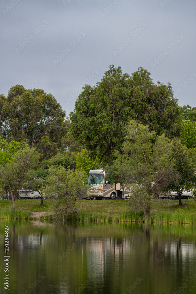Fototapeta premium Rv Camping along the shore at Lake Camanche in the spring with reflection in water