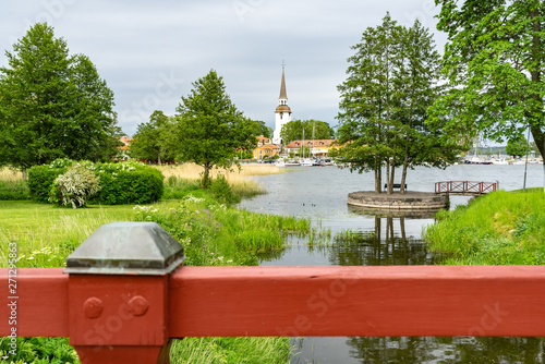 Mariefred, Swedish town  in Sodermanland, mirrored in the water. White church made of stone. High bell tower of local church (Mariefred Charter house) Panorama.  photo