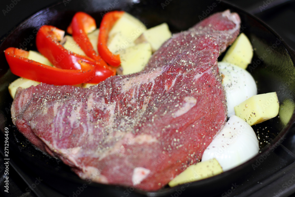 Sirloin tritip steak in a cast iron pan with potatoes and onions on the