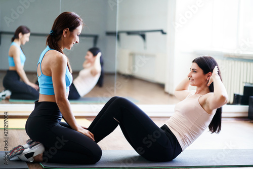 Personal trainer, teamwork, workout, perfect shape. Fit sporty woman doing sit-ups with fitness instructor support