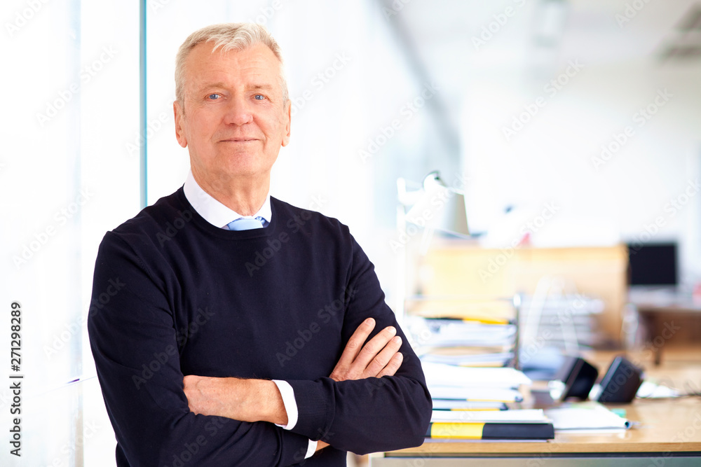 Fototapeta premium Elderly businessman portrait while standing with their arms crossed