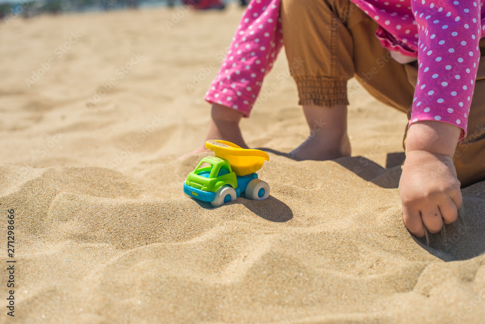 Kid's hand playing with a toy truck in the sand Kid's hand playing with a toy truck in the sand