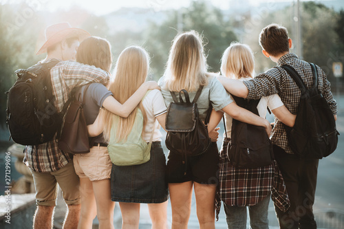 Friendship, togetherness, traveling, vacation, holidays, togetherness, sightseeing, city tour, student exchange program. Young people with backpacks standing close hugging admiring the city view
