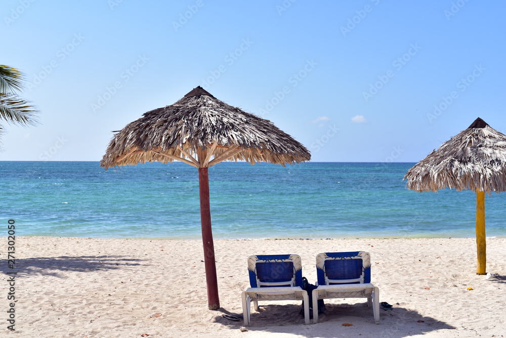 Empty sunbeds under a parasol on the beach of Playa Ancon near Trinidad, Cuba