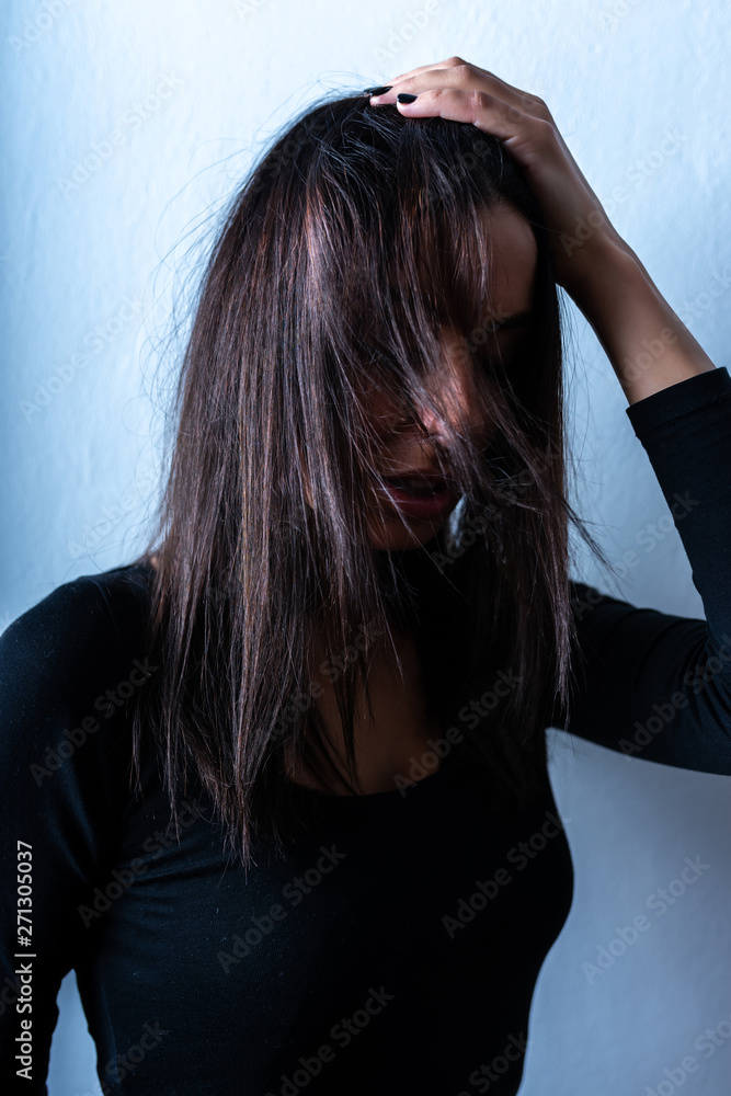 Fototapeta premium Dark mood portrait of a woman in front of a wall