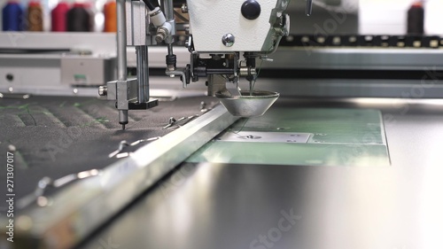 Robotics works in tailoring production line. Robot sewing machine. an automated machine embroidery pattern with red threads on a black cloth. automatic sewing machine.