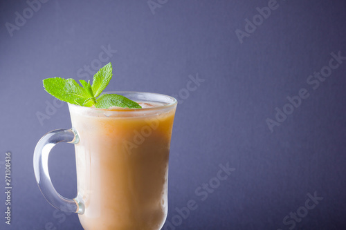 Iced coffee with milk on a dark background. Latte and fresh mint on a slate board. Summer drink in a glass, and coffee beans. Copy space