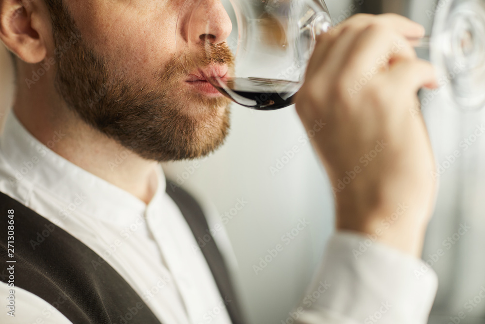 Extreme closeup of handsome bearded man drinking wine during tasting session in restaurant, copy space Extreme closeup of handsome bearded man drinking wine during tasting session in restaurant, copy space