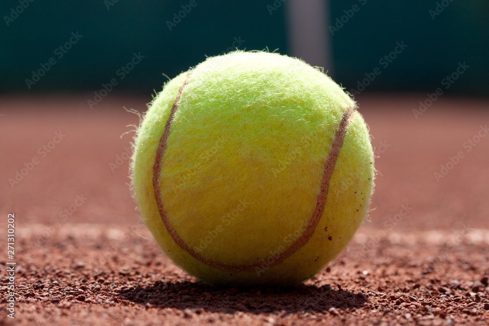 Close up of tennis ball on clay court.